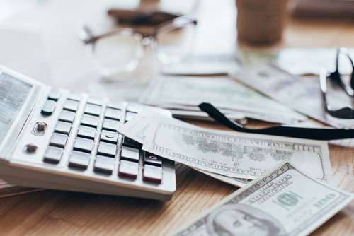 cash dollars on a table in front of a calculator